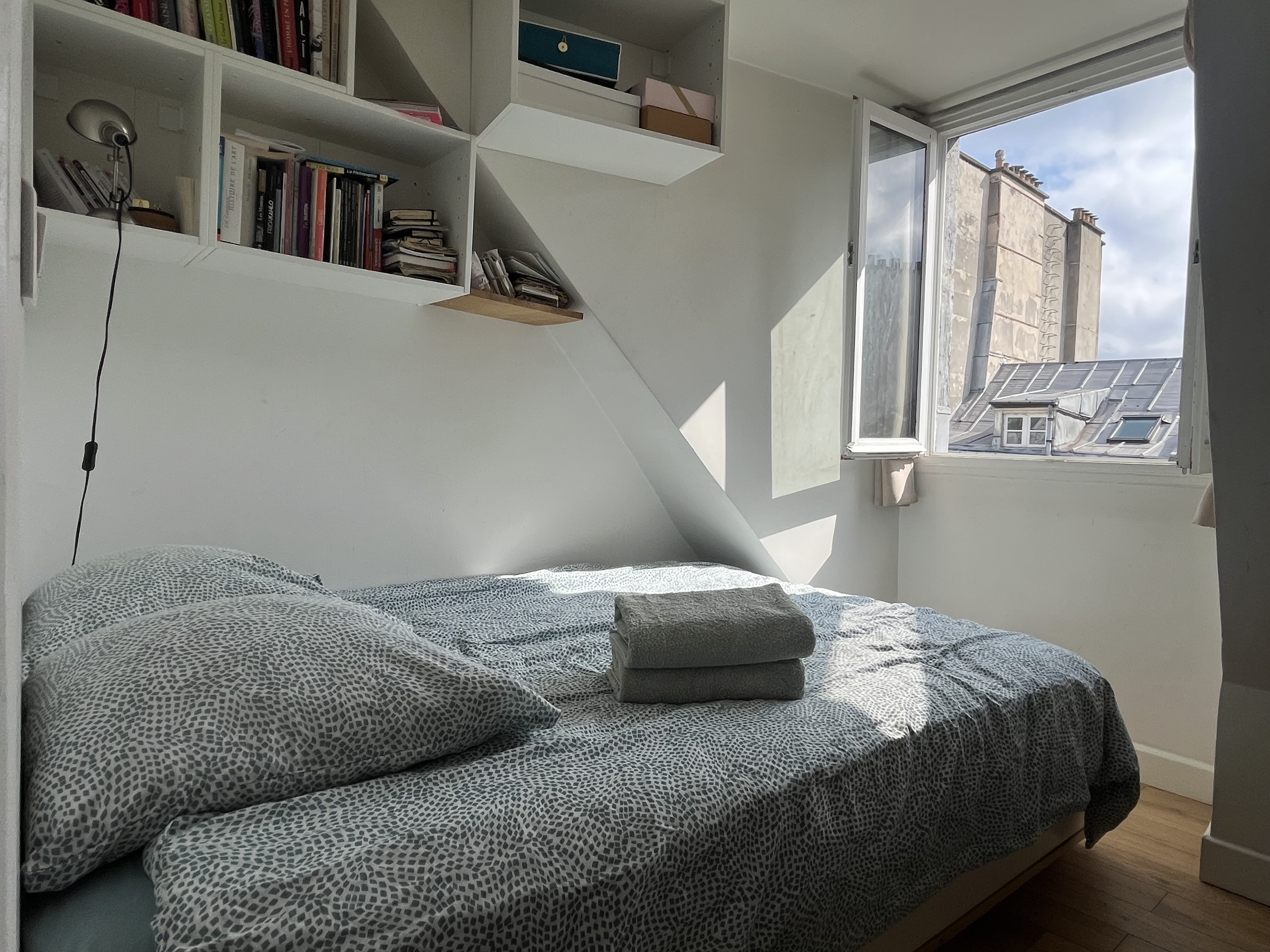 Bedroom with a double bed and a window overlooking Paris rooftops